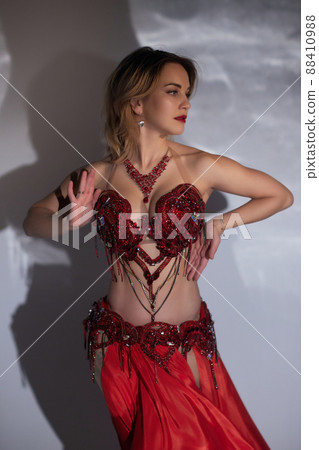 Beautiful girl with long black hair in a red oriental dress dancing belly dance in the studio room. Arab culture. Beautiful girl with long black hair in a red oriental dress dancing belly dance in the studio room. Arab culture. 88410988