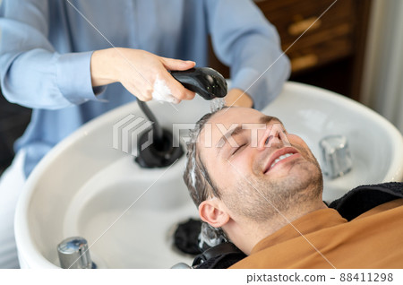 Hairdresser washing hair to the male client in a beauty salon Hairdresser washing hair to the male client in a beauty salon 88411298