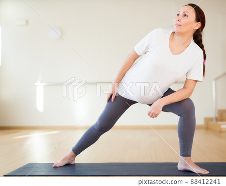 Pregnant woman is engaged in yoga. Extended Side Angle or Utthita Parsvakonasana 88412241