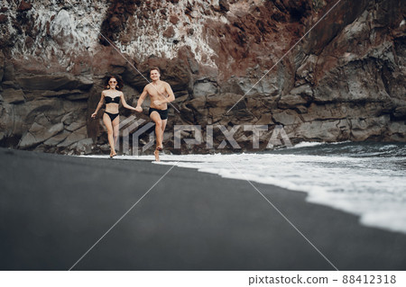 couple relaxing at a secluded private beach in Bali Indonesia. couple showing affection on a hidden beach. Couple wearing bathingsuits couple relaxing at a secluded private beach in Bali Indonesia. couple showing affection on a hidden beach. Couple wearing bathingsuits 88412318