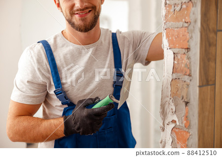 Cropped shot of worker or craftsman using spatula and plastering old cement wall with putty 88412510