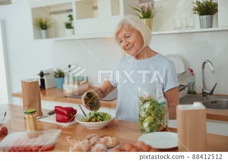 Pension age good looking woman eating green salad indoors 88412512