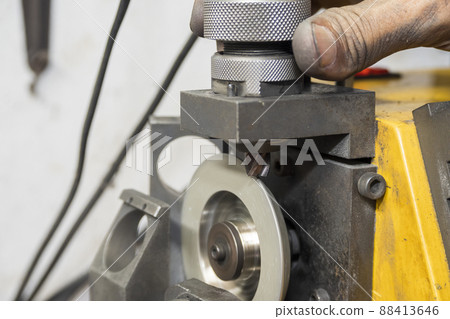 The worker regrinding the end mill tool with end mill sharpening machine. 88413646