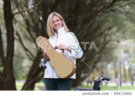 Smiling young woman holding guitar or violin case 88413660