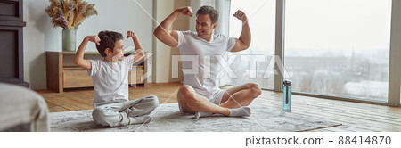 Cheerful father and son demonstrating muscles at home Cheerful father and son demonstrating muscles at home 88414870