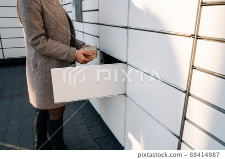 Delivery locker. Post automat terminal and hands with parcel courier box. Online purchase delivery service concept. 88414987
