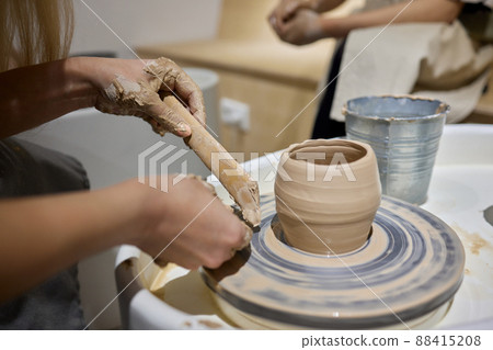 Close up shot of hands of crafts people, working with clay in pottery studio. 88415208