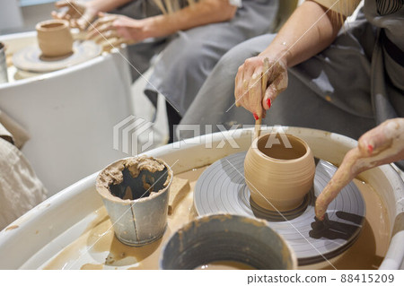Close up shot of hands of crafts people, working with clay in pottery studio. 88415209