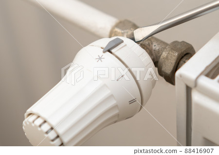 Adjusting temperature on heating radiator thermostat and screwdriver to repair. Adjusting temperature on heating radiator thermostat and screwdriver to repair. 88416907