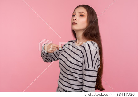 This is me. Portrait of arrogant woman in striped sweatshirt pointing herself and looking selfish egoistic haughty, feeling proud of own achievement. indoor studio shot isolated on pink background 88417326