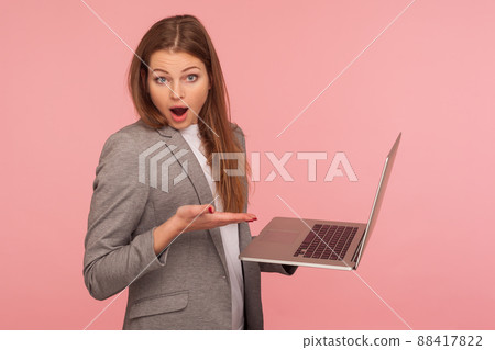 Portrait of astonished businesswoman holding laptop and looking at camera with amazed face, using computer to study, working online, shocked by application. studio shot isolated on pink background Portrait of astonished businesswoman holding laptop and looking at camera with amazed face, using computer to study, working online, shocked by application. studio shot isolated on pink background 88417822