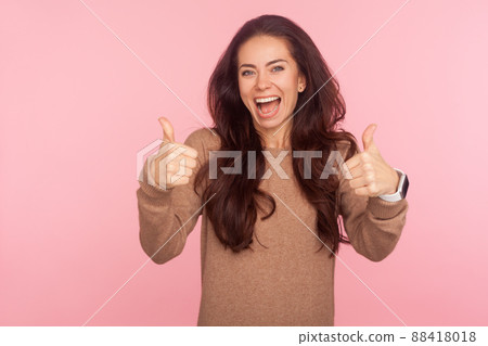 Excellent job, well done. Portrait of joyful awesome young woman with brunette wavy hair showing like gesture, thumbs up or approval sign to successful project. studio shot isolated on pink background Excellent job, well done. Portrait of joyful awesome young woman with brunette wavy hair showing like gesture, thumbs up or approval sign to successful project. studio shot isolated on pink background 88418018