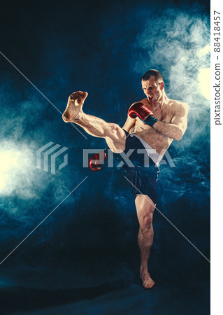 Full size of Muay thai fighter who kicks in the air, shadow boxing isolated on smoke background. The concept of sports, mixed martial arts. Full size of Muay thai fighter who kicks in the air, shadow boxing isolated on smoke background. The concept of sports, mixed martial arts. 88418457