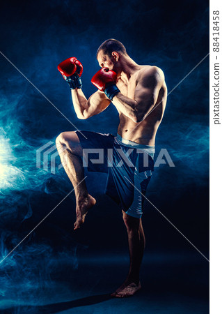 Full size of Muay thai fighter who delivering knee hit isolated on smoke background. mixed media Full size of Muay thai fighter who delivering knee hit isolated on smoke background. mixed media 88418458