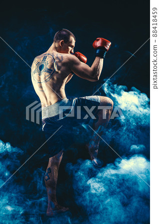 Full size of Muay thai fighter who delivering knee hit isolated on smoke background. mixed media Full size of Muay thai fighter who delivering knee hit isolated on smoke background. mixed media 88418459