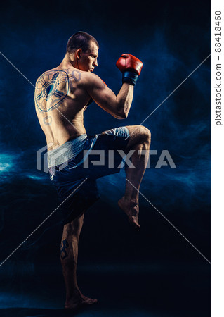 Full size of Muay thai fighter who delivering knee hit isolated on smoke background. mixed media  88418460