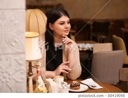Beautiful overweight woman at table in cafe. Plus size model 88419098