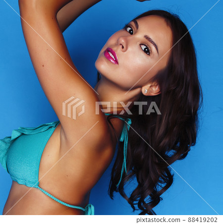 young pretty brunette girl in bikini smiling studio blue background, lifestyle people concept 88419202