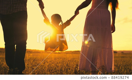 mother father kid daughter summer park sunset. child kid holding parents hands. happy family holiday. runs jumps up kid child. mom dad baby girl walk along green meadow park. family vacation innature. 88419274