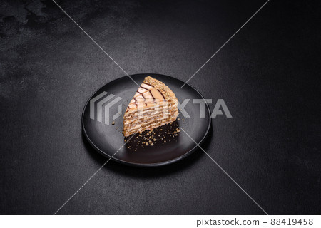 Esterhazy cake sliced on black plate close-up. Delicatessen sweet dessert with almond meringue dough and buttercream 88419458
