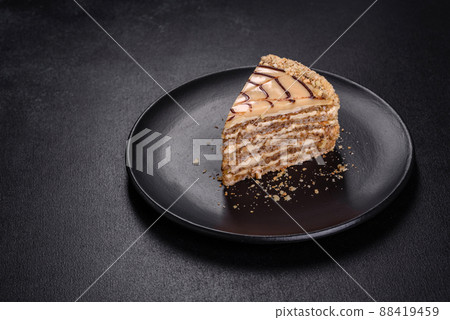 Esterhazy cake sliced on black plate close-up. Delicatessen sweet dessert with almond meringue dough and buttercream 88419459