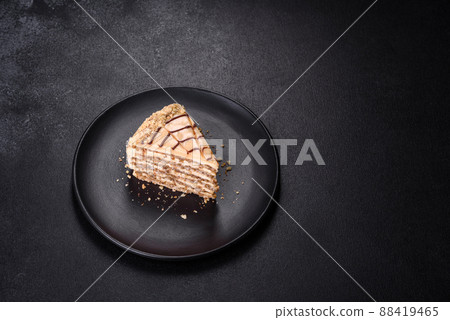 Esterhazy cake sliced on black plate close-up. Delicatessen sweet dessert with almond meringue dough and buttercream 88419465