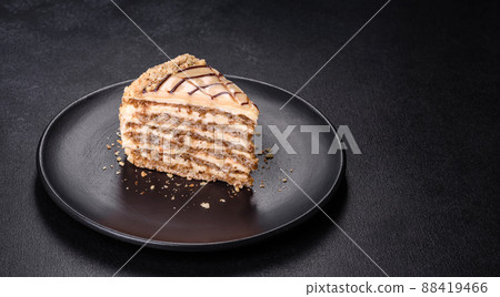 Esterhazy cake sliced on black plate close-up. Delicatessen sweet dessert with almond meringue dough and buttercream 88419466