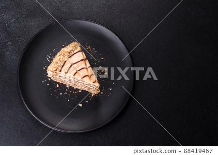 Esterhazy cake sliced on black plate close-up. Delicatessen sweet dessert with almond meringue dough and buttercream 88419467