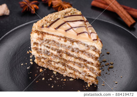 Esterhazy cake sliced on black plate close-up. Delicatessen sweet dessert with almond meringue dough and buttercream 88419472