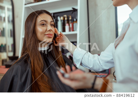 Young female customer getting blush powder on her cheek with a brush 88419612