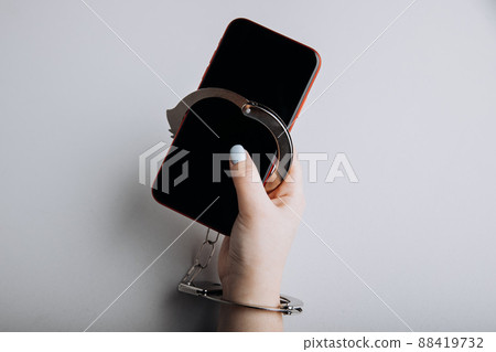 Smartphone addiction concept. Phone chained to handcuff in hand Smartphone addiction concept. Phone chained to handcuff in hand 88419732