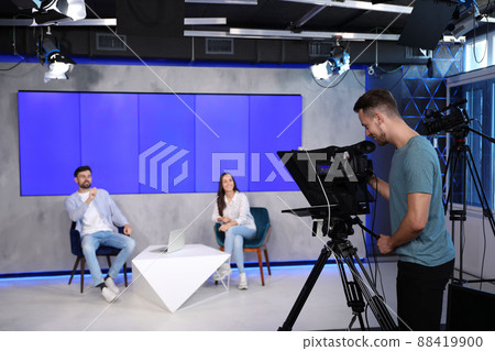 Presenters and video camera operator working in studio. News broadcasting 88419900