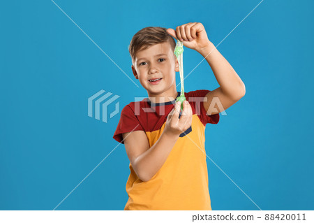 Preteen boy with slime on blue background Preteen boy with slime on blue background 88420011