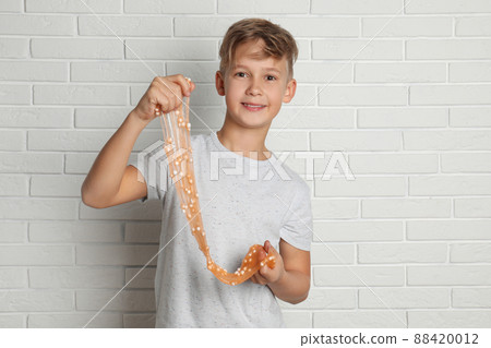 Preteen boy with slime near white brick wall Preteen boy with slime near white brick wall 88420012