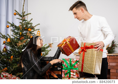 The bride and groom collected a lot of packages with gifts for this year's Christmas. A unique Christmas atmosphere. Shiny black dress. 88420073