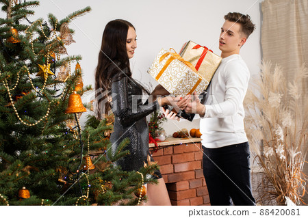 The groom gives a gift to his beloved in a shiny dress on Christmas Day. A unique Christmas atmosphere. A surprise during the holidays. 88420081