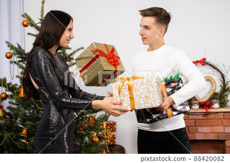 The groom gives a gift to his beloved in a shiny dress on Christmas Day. A unique Christmas atmosphere. A surprise during the holidays. 88420082