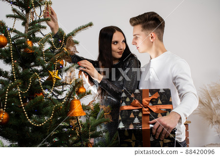 Just before the meeting starts, the bride and groom are decorating the Christmas tree at home for Christmas. Christmas decorations. The girl and the boy work together. 88420096