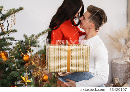 The boy lifted his beloved soybeans up for joy. A couple in love hug by the Christmas tree in their living room. A unique Christmas atmosphere. 88420107