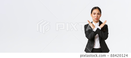 Serious-looking confident businesswoman in black suit showing cross gesture to forbid action, restrict, forbid or prohibit making any deals, stop working with client, white background. Time out Serious-looking confident businesswoman in black suit showing cross gesture to forbid action, restrict, forbid or prohibit making any deals, stop working with client, white background. Time out 88420124