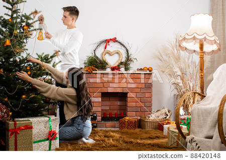 Decorated guest room for Christmas by a couple in love. A warm Christmas atmosphere by the Christmas tree and fireplace. Decorated guest room for Christmas by a couple in love. A warm Christmas atmosphere by the Christmas tree and fireplace. 88420148