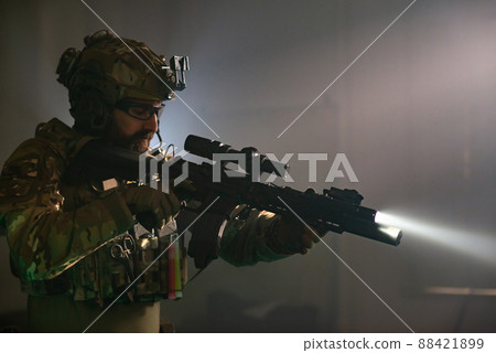 Absorbed bearded man in military equipment in dark room Absorbed bearded man in military equipment in dark room 88421899