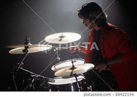 Concentrated young man playing drum set at concert Concentrated young man playing drum set at concert 88422134