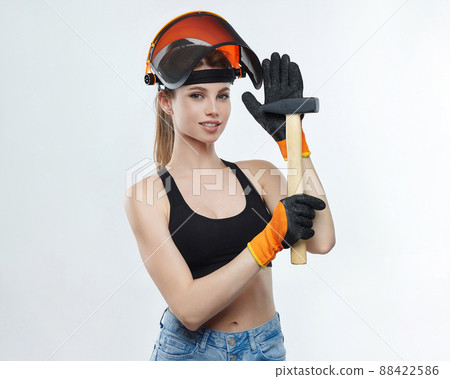attractive blonde in an orange protective helmet with a hammer in her hands. attractive blonde in an orange protective helmet with a hammer in her hands. 88422586