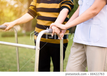 Nurse helping elderly woman hands holding walker trying to walking at outdoor,Care nursing home concept,Physical therapy 88422763