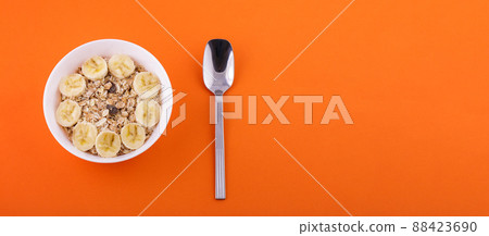 oatmeal in a plate with a banana and a spoon on an orange background oatmeal in a plate with a banana and a spoon on an orange background 88423690
