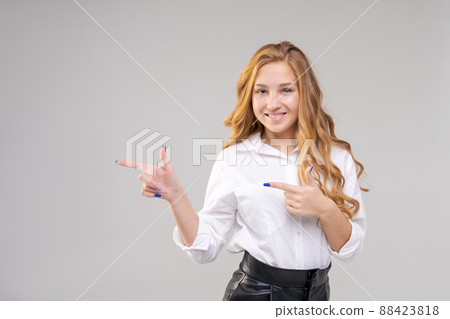 Reliable cheerful girl in white shirt points her finger at an empty space 88423818