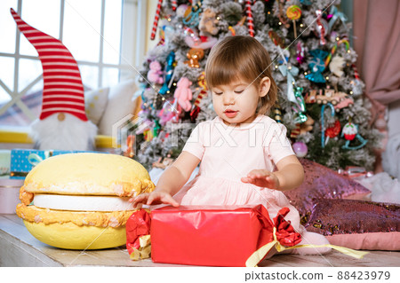a little girl plays near the Christmas tree 88423979