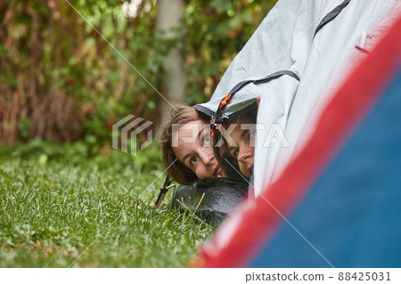 Rain falling on tents, girls peeking out 88425031