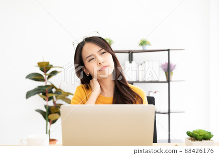 Young asian woman feeling pain in neck and shoulder after working on computer laptop for a long time Young asian woman feeling pain in neck and shoulder after working on computer laptop for a long time 88426176